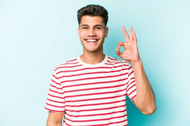 Kafkasyalı genç adam mavi arka planda izole edilmiş neşeli ve kendinden emin..