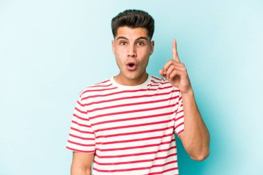 Kafkasyalı genç bir adam mavi arka planda izole edilmiş. Bir fikri, ilham verici bir fikri var..