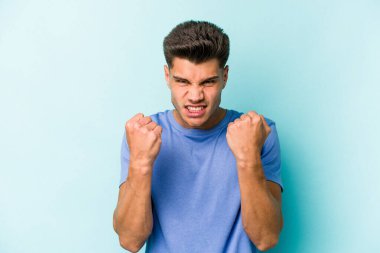 Mavi arka planda izole edilmiş genç beyaz adam gergin elleriyle çığlık atıyor..