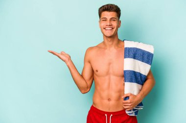 Elinde plaj havlusu tutan beyaz bir adam mavi arka planda bir fotokopi alanı ve belinde bir el daha gösteriyor..