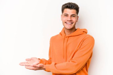 Beyaz arka planda izole edilmiş beyaz tenli genç bir adam palmiyesinde bir kopya alanı tutuyor..