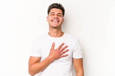 Beyaz arka planda izole genç beyaz adam yüksek sesle gülüyor elini göğsüne koyuyor..