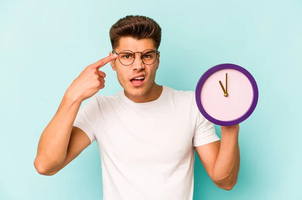 Young Caucasian Man Holding Clock Isolated Blue Background Showing Disappointment —  Fotos de Stock