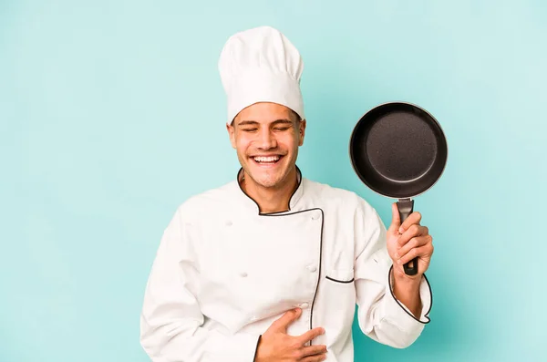 年轻的高加索厨师拿着被蓝色背景隔开的飞行锅 笑着玩乐 — 图库照片
