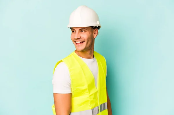 Young Laborer Caucasian Man Isolated Blue Background Looks Aside Smiling — 스톡 사진