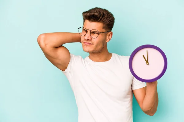 Young Caucasian Man Holding Clock Isolated Blue Background Touching Back — Foto de Stock