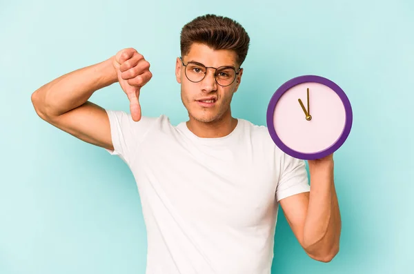 Young Caucasian Man Holding Clock Isolated Blue Background Showing Dislike — Photo