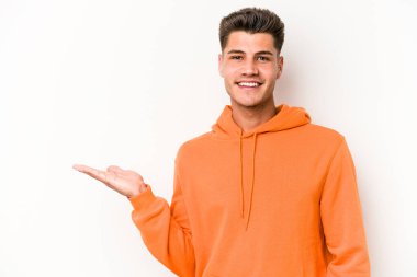 Beyaz arka planda izole edilmiş genç beyaz bir adam bir palmiye üzerinde fotokopi alanı gösteriyor ve belinde başka bir el tutuyor..