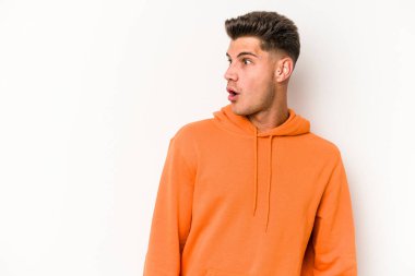 Beyaz arka planda izole edilmiş genç beyaz adam gördüğü bir şey yüzünden şoka uğruyor..