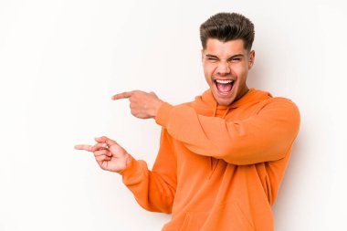 Beyaz arka planda izole edilmiş genç beyaz bir adam işaret parmağıyla fotokopi alanını işaret ederek heyecan ve arzusunu ifade ediyor..