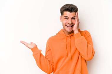 Beyaz arka planda izole edilmiş genç beyaz bir adam bir avuç içinde fotokopi alanı tutuyor, el üstünde tutuyor. Şaşırmış ve mutlu..