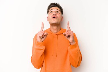 Beyaz arka planda izole edilmiş genç beyaz adam ağzı açık bir şekilde üst tarafı işaret ediyor..