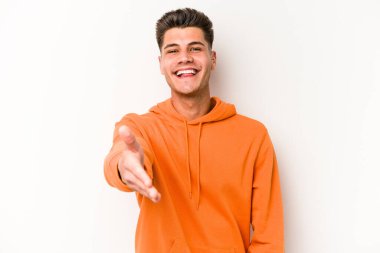 Beyaz arka planda izole edilmiş genç beyaz bir adam selamlama jesti olarak kameraya elini uzatıyor..