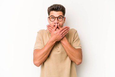 Beyaz arka planda izole edilmiş genç beyaz adam elleriyle ağzını kapatırken şok oldu..