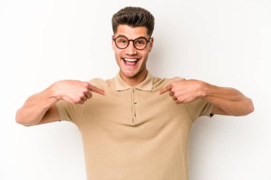 Beyaz arka planda izole edilmiş genç beyaz bir adam parmağını göstererek şaşırdı, geniş bir gülümsemeyle..