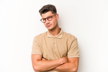 Beyaz arka planda izole edilmiş genç beyaz bir adam şüpheli, belirsiz, seni muayene ediyor..