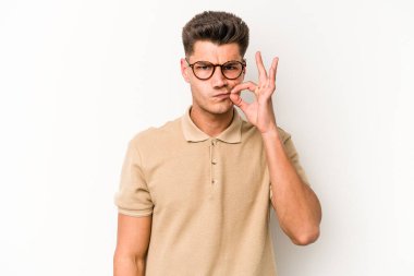 Beyaz arka planda izole edilmiş beyaz tenli genç bir adam parmakları dudaklarında bir sır saklıyor..