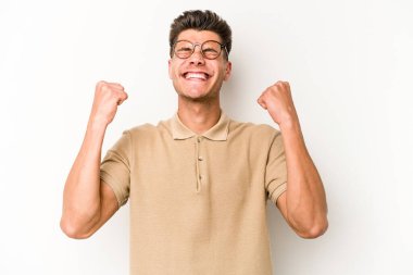 Beyaz arka planda izole edilmiş genç beyaz bir adam zaferi, tutkuyu ve coşkuyu kutluyor, mutlu bir ifade..