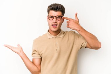 Beyaz arka planda izole edilmiş genç beyaz bir adam elinde bir ürün tutuyor ve.