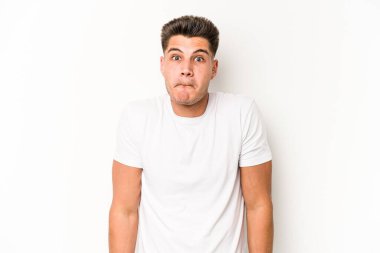 Beyaz arka planda izole edilmiş genç beyaz bir adam omuz silkiyor ve gözleri açık..