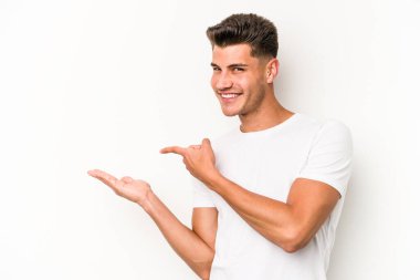 Beyaz arka planda izole edilmiş genç beyaz bir adam, palmiye üzerinde bir fotokopi alanı tutarken heyecanlı..