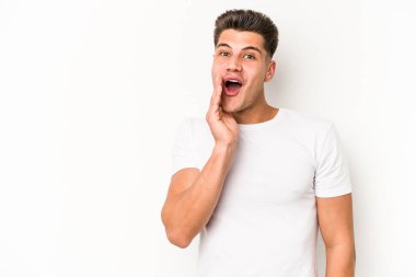 Beyaz arka planda izole genç beyaz adam yüksek sesle bağırıyor, gözleri açık ve elleri gergin tutuyor..