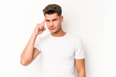 Beyaz arka planda izole edilmiş genç beyaz bir adam şakağı parmağıyla işaret ediyor, düşünüyor ve bir göreve odaklanıyor..