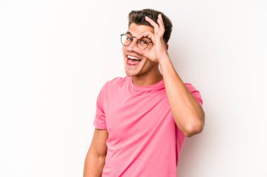 Beyaz arka planda izole genç beyaz adam heyecanlı tamam göz jesti tutmak.