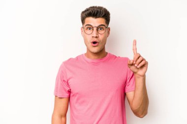 Beyaz arka planda izole edilmiş genç beyaz adam ağzı açık bir şekilde üst tarafı işaret ediyor..