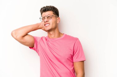 Beyaz arka planda izole edilmiş genç beyaz bir adam yorgun ve uykulu bir şekilde elini başının üstünde tutuyor..