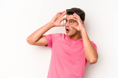 Beyaz arka planda izole edilmiş genç beyaz bir adam bir başarı fırsatı bulmak için gözlerini açık tutuyor..