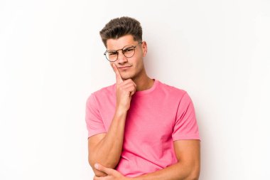 Beyaz arka planda izole edilmiş genç beyaz adam alaycı bir ifadeyle kameraya bakıyor..