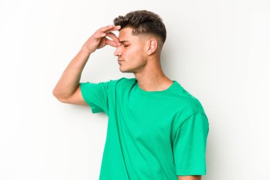 Beyaz arka planda izole olmuş genç beyaz bir adam başı ağrıyor, yüzüne dokunuyor..