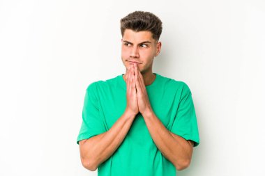 Beyaz arka planda izole edilmiş genç beyaz adam dua ediyor, bağlılık gösteriyor, dindar biri ilahi ilham arıyor..