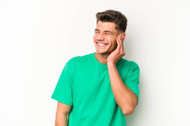 Beyaz arka planda izole edilmiş genç beyaz bir adam parmaklarıyla kulaklarını kapatıyor, gürültülü bir ortam yüzünden stresli ve çaresiz..