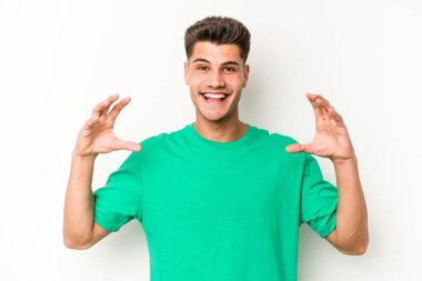 Beyaz arka planda izole edilmiş genç beyaz bir adam elinde avuç içi bir şeyle kameraya sunuyor..