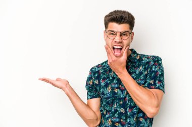 Beyaz arka planda izole edilmiş genç beyaz bir adam bir avuç içinde fotokopi alanı tutuyor, el üstünde tutuyor. Şaşırmış ve mutlu..