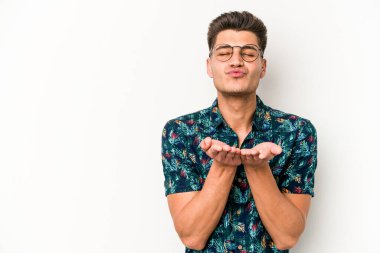 Beyaz arka planda izole edilmiş genç beyaz bir adam dudaklarını katlıyor ve hava öpücüğü vermek için avuç içleri tutuyor..