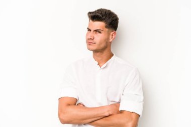 Beyaz arka planda izole edilmiş genç beyaz adam alaycı bir ifadeyle kameraya bakıyor..