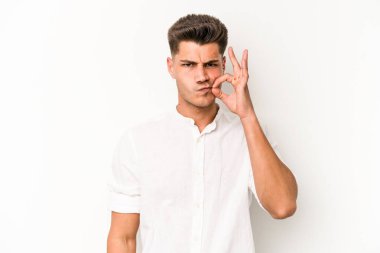 Beyaz arka planda izole edilmiş beyaz tenli genç bir adam parmakları dudaklarında bir sır saklıyor..