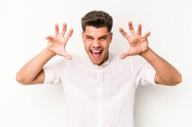 Beyaz arka planda izole edilmiş genç beyaz bir adam pençelerini kedi taklidi yaparken gösteriyor, agresif bir hareket..