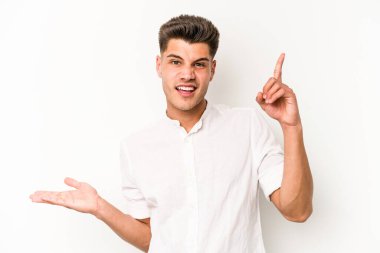 Beyaz arka planda izole edilmiş genç beyaz bir adam elinde bir ürün tutuyor ve.