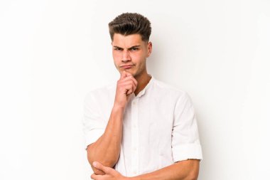 Beyaz arka planda soyutlanmış genç beyaz bir adam düşünüyor ve yukarı bakıyor, yansıtıyor, düşünüyor, hayal kuruyor..