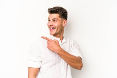 Beyaz arka planda izole edilmiş genç beyaz adam gülümseyen, neşeli ve keyifli bir tarafa bakıyor..