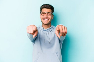 Mavi arka planda izole edilmiş genç beyaz adam öne bakan neşeli gülümsemeler.