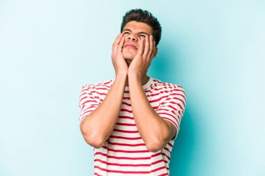 Kafkasyalı genç adam mavi arka planda izole edilmiş sızlanıyor ve ağlıyordu..