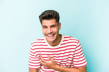 Kafkasyalı genç adam mavi arka planda izole edilmiş gülüyor ve eğleniyor..