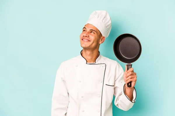 年轻的高加索厨师拿着飞行锅 与蓝色背景隔离 梦想着实现自己的目标和宗旨 — 图库照片
