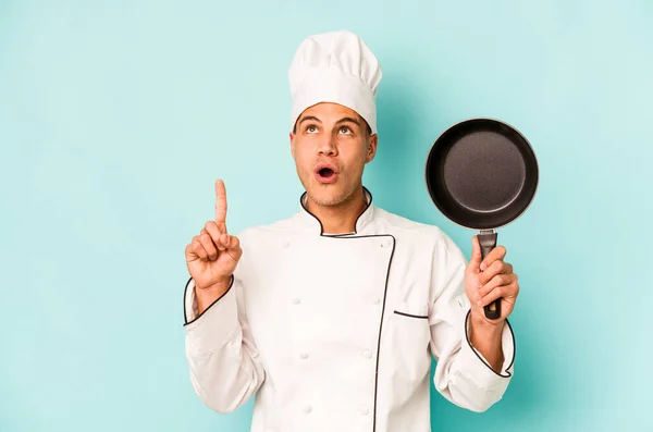 年轻的高加索厨师手持飞行锅 隔离在蓝色背景中 顶部有开口 — 图库照片