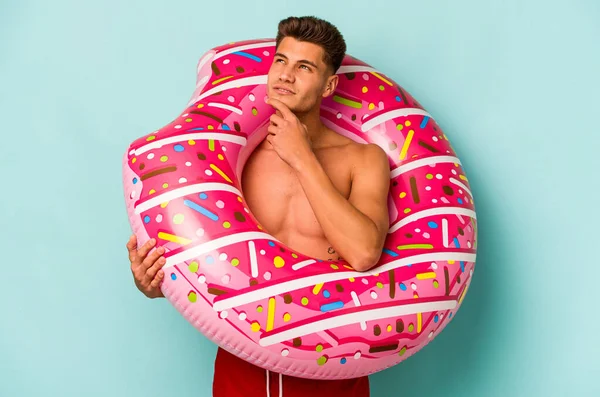Young Caucasian Man Holding Inflatable Donut Isolated Blue Background Looking — Stock fotografie